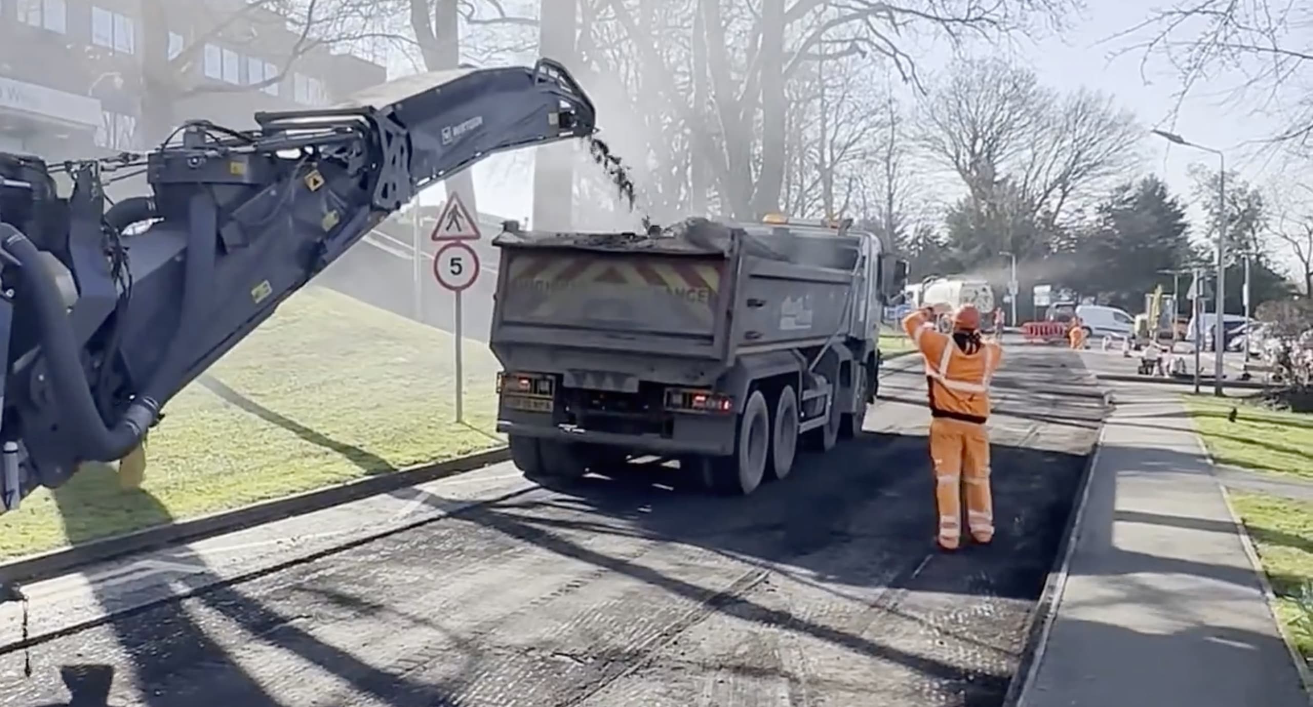 Asphalt cold milling machine loading planings into a tipper lorry during public road works